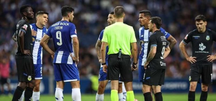 Jogadores de FC Porto e Arouca rodeiam o árbitro Miguel Nogueira.